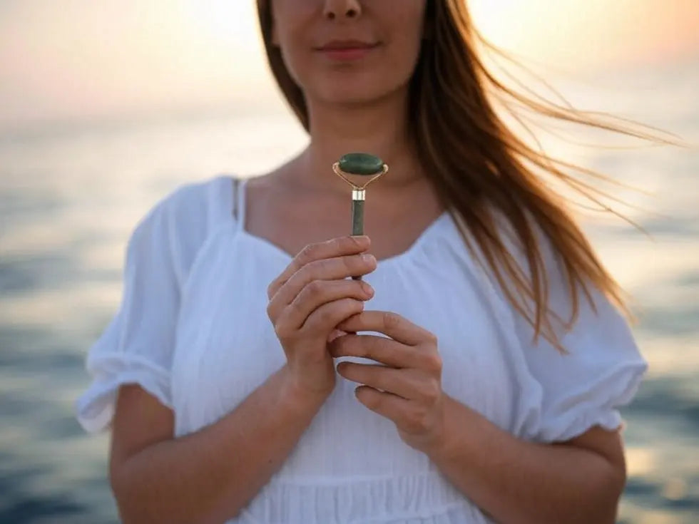 femme qui tient un roller gua sha jade face à la mer